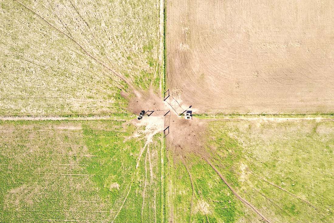 Aerial view of four paddocks meeting at a fence corner, with gates and water troughs where the boundaries cross